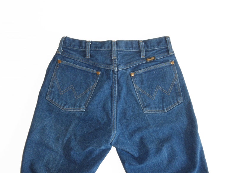 May include: A pair of blue denim jeans with a classic five-pocket design. The back pockets feature a stitched 'W' logo.