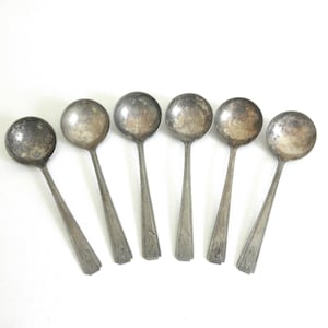 May include: Six vintage silver soup spoons with round bowls and long, slender handles. The spoons have a tarnished, aged appearance, suggesting they are antique or well-used. The handles have a decorative pattern near the base.