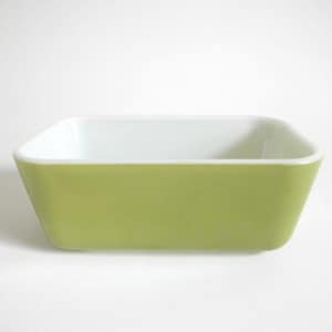 May include: A rectangular, light green dish with a white interior. The dish has a slightly tapered design and rounded corners. The object is likely a baking dish or serving bowl.