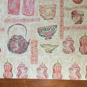 Puede incluir: Un patr&oacute;n repetido de teteras, cuencos y calabazas de estilo japon&eacute;s rosa y rojo sobre un fondo crema. El patr&oacute;n recuerda a una tradicional ceremonia japonesa del t&eacute;.