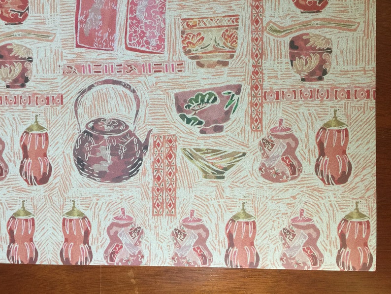 Puede incluir: Un patr&oacute;n repetido de teteras, cuencos y calabazas de estilo japon&eacute;s rosa y rojo sobre un fondo crema. El patr&oacute;n recuerda a una tradicional ceremonia japonesa del t&eacute;.