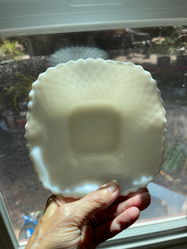 May include: A white milk glass square dish with a scalloped edge. The dish has a textured surface and is slightly iridescent.
