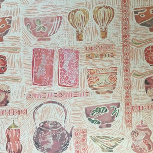 Puede incluir: Un fondo estampado en rosa y blanco con varios cuencos rojos y marrones, teteras y otros utensilios de cocina. El patr&oacute;n recuerda a las estampas japonesas en madera.