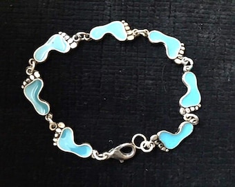 Pulsera o tobillera con huellas de pies. 16,5 cm de largo. Delicadas huellas de pies esmaltadas en azul unidas entre sí. Joyería playera vintage.