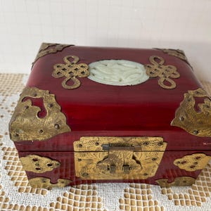 Vintage Jewelry Box. Red lacquered wood box with engraved brass fittings and green carved jade decoration on top. Very pretty. Chinese Box.