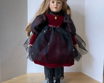 Vintage Girl Doll in Victorian dress. She is 17-1/2" tall and has porcelain head, arms and legs nd long blonde hair. Display stand included.