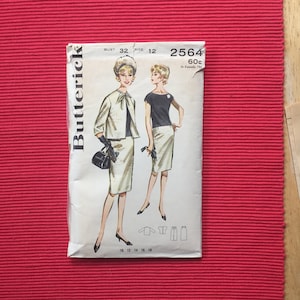Pu&ograve; includere: Una busta per cartamodello Butterick 2564, taglia 12, busto 32. Il fronte presenta illustrazioni di due outfit: un completo giacca e gonna chiaro con un top scuro, e un top scuro a maniche corte con una gonna chiara. Include testo e diagrammi.