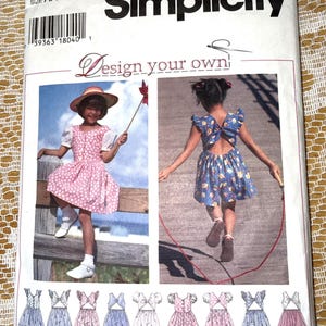 May include: A Simplicity sewing pattern envelope, number 9573, size AA 3, 4, 5, 6. The front features two photographs of children wearing dresses and rompers, with the text Design your own. Below are eight line drawings of various garment styles.