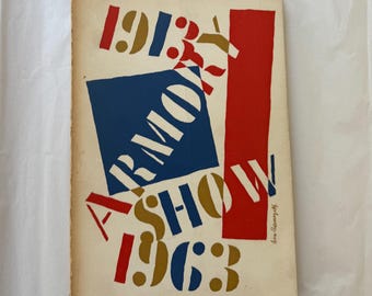 May include: Vintage art exhibition catalog titled "Armory Show 1913-1963." The cover features bold typography and geometric shapes in red, blue, and gold against a cream background. The design is a striking example of mid-century modern graphic design.