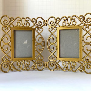 Moldura dupla vintage sofisticada para fotos. Detalhes em dourado com 2,5 cm de largura em toda a volta. Dimensões totais (aproximadamente): 23 cm de largura x 14 cm de altura (com a moldura aberta).