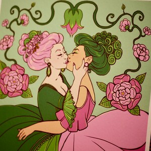 May include: Two women with pink and green hair are kissing. They are wearing elaborate dresses with floral patterns. The background is a light green with vines and pink flowers.