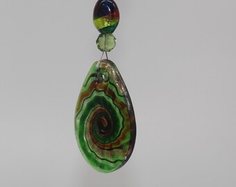 May include: A decorative glass pendant with a spiral design in shades of green, brown, and black. The pendant is connected to a string of colorful beads, including red and iridescent oval beads, and green crystal beads.