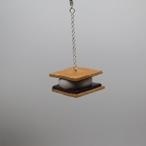 May include: A miniature s'more charm with a graham cracker, chocolate, and marshmallow, hanging from a silver chain.