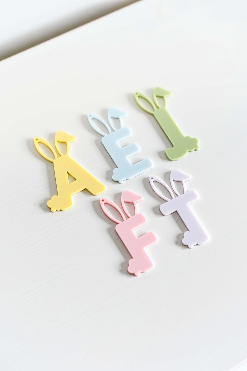 May include: Five pastel colored acrylic letters with bunny ears. The letters spell out the word "A E F T".