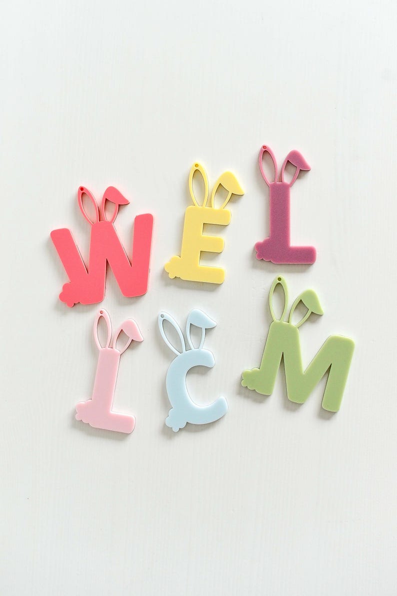 May include: A set of six pastel-colored letters spelling out "WELCOME" with bunny ears on top. The letters are made of a thick, plastic material and are perfect for decorating a home or classroom.
