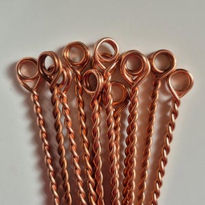 May include: A group of ten copper wire pieces with a twisted design. Each piece has a loop at one end.