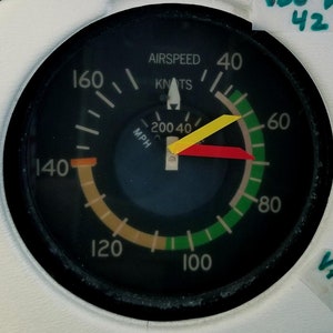 May include: A black and white airspeed indicator with a yellow and red needle. The gauge reads 40 knots and 40 mph. The gauge is labeled "airspeed" and "knots".