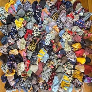 May include: A rug constructed from a dense collection of folded neckties in a wide variety of colors and patterns, including stripes, polka dots, and geometric prints, creating a textured, multi-colored surface with a layered appearance.