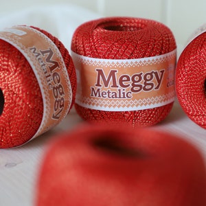 May include: Four red balls of yarn with gold metallic thread. The yarn is labeled "Meggsy Metallic".