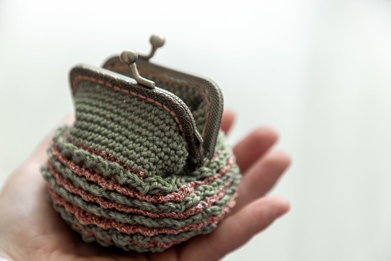 May include: A small crocheted coin purse with a silver clasp. The purse is green with a pink trim.