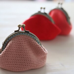 May include: Three crocheted coin purses with metal clasps. The purses are pink, red, and red. The pink purse has a blue trim around the clasp.