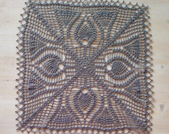 May include: A square, gray crocheted doily with an intricate openwork design. The center features a symmetrical pattern with floral and geometric elements. The edges are finished with a scalloped border, creating a delicate and textured appearance.