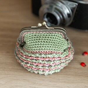 May include: A green crocheted coin purse with a pink trim and a silver clasp.