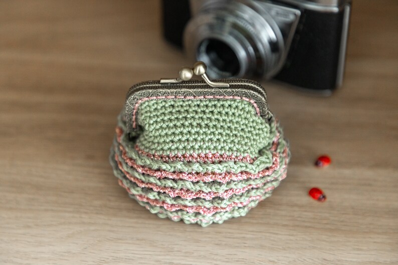 May include: A green crocheted coin purse with a pink trim and a silver clasp.