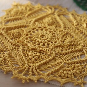 May include: A yellow crocheted doily with a delicate floral pattern. The doily is made with fine yarn and has a lacy, intricate design.