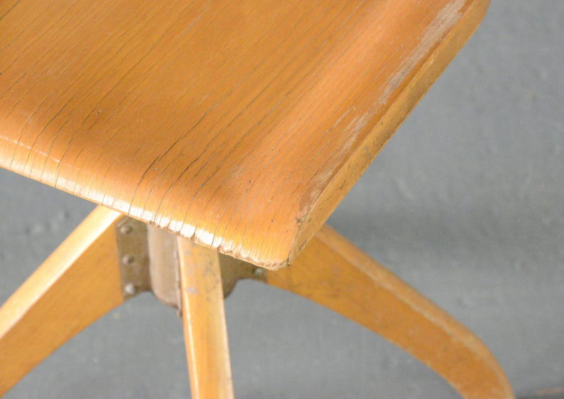 Op de afbeelding: Een houten stoel met een lichtbruine afwerking en een stervormige basis. De stoel heeft een eenvoudig ontwerp en is gemaakt van massief hout.