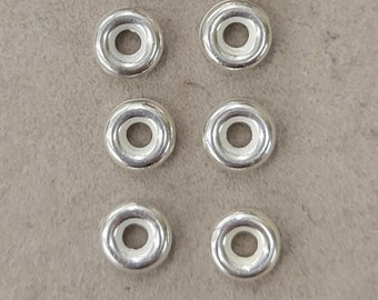 Könnte beinhalten: Ein Satz von zwölf silbernen Metallösen mit weißen Kunststoffeinsätzen. Die Ösen sind in vier Reihen zu je drei angeordnet.