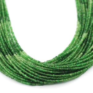 May include: A multi-strand necklace composed of numerous tiny, round, faceted green beads. The beads exhibit varying shades of emerald and forest green, creating a gradient effect throughout the strands. The necklace is arranged in a U-shape.