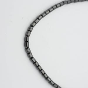May include: A black beaded necklace made of small, cylindrical beads.