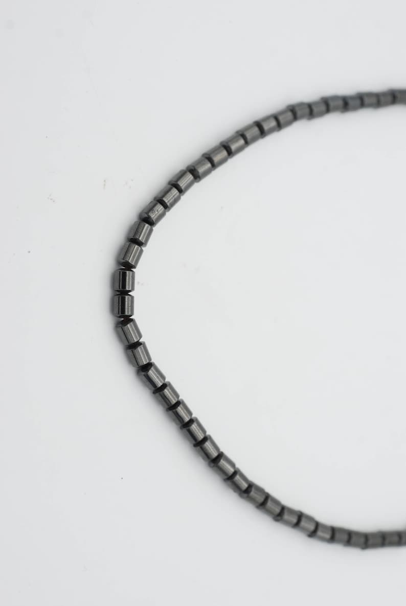 May include: A black beaded necklace made of small, cylindrical beads.