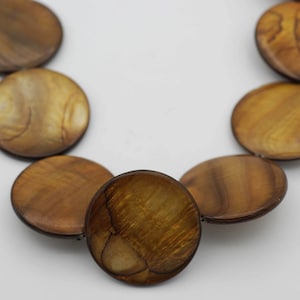 May include: A necklace made of round, brown and gold shell beads.