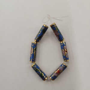 K&ouml;nnte beinhalten: Eine Reihe von sechs blauen Emailleperlen mit goldenen Verzierungen und Blumenmustern. Die Perlen sind auf einem durchsichtigen Faden aufgef&auml;delt.