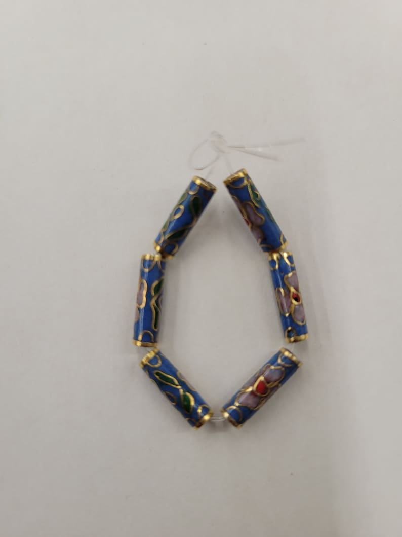 K&ouml;nnte beinhalten: Eine Reihe von sechs blauen Emailleperlen mit goldenen Verzierungen und Blumenmustern. Die Perlen sind auf einem durchsichtigen Faden aufgef&auml;delt.