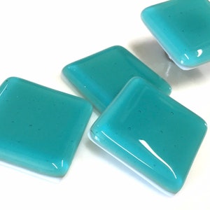 Puede incluir: Cuatro pomos cuadrados de armario de vidrio azul verdoso con un acabado moteado.