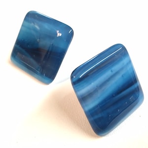 May include: Two square-shaped glass tiles with a blue and white marbled pattern. The tiles have a slightly translucent appearance.