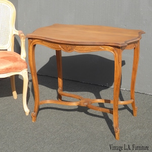May include: A vintage wooden table with a carved design on the top and legs. The table has a light brown finish and is in good condition.