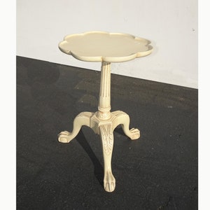 May include: Ivory-colored accent table with a scalloped top. The table has a fluted column and three claw feet. The table is approximately 28 inches tall.