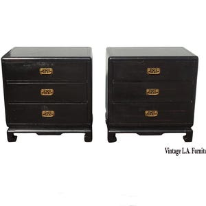 May include: Two black nightstands with three drawers each, featuring ornate gold-colored drawer pulls. The nightstands have a classic design with a slightly curved base. The text "Vintage L.A. Furniture" is visible in the bottom right corner.