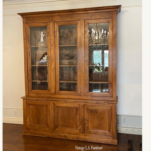 May include: A large, antique wooden cabinet with glass doors and drawers. The cabinet has a rich brown color and is made of solid wood. It features intricate details and decorative hardware. The cabinet is perfect for displaying collectibles or storing books.