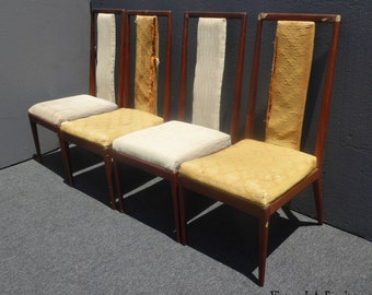 May include: Set of four mid-century modern dining chairs with a wood frame and upholstered seats. The chairs have a light brown wood frame and beige and yellow fabric upholstery.