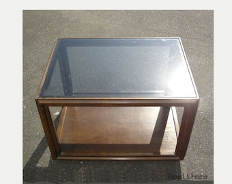 May include: A dark wood coffee table with a glass top and a lower shelf. The table has a simple, rectangular design.