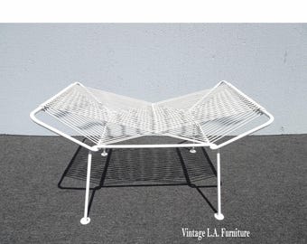 May include: A white, mid-century modern style bench with a geometric design. The bench features a white metal frame and a woven seat. The legs are thin and straight, with small, round feet. The bench is approximately 36 inches long.