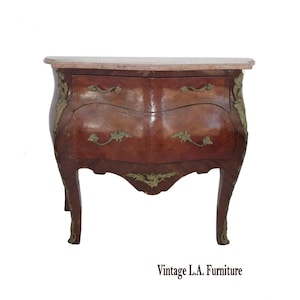 May include: A vintage wooden chest of drawers with a marble top. The chest has two drawers with brass handles and decorative accents. The wood has a rich, reddish-brown finish. The text "Vintage L.A. Furniture" is at the bottom.