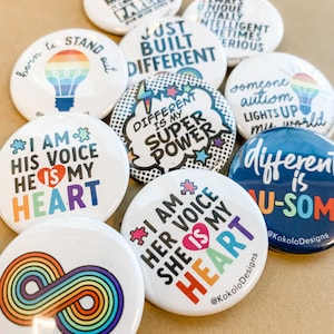 May include: A collection of ten round button pins with various designs and messages related to autism awareness. The buttons feature rainbow colors, stars, and text such as "I am his voice, he is my heart", "Different is my super power", "Just built different", and "Someone autism lights up my world".