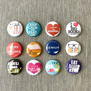 May include: Twelve round button pins with various book-themed sayings. The pins are colorful and feature a variety of designs, including books, hearts, glasses, and words. The pins are perfect for book lovers and would make a great gift.