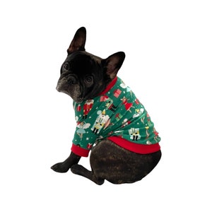 May include: A black and brindle French Bulldog wearing a green Christmas sweater with a red trim. The sweater features a festive pattern of nutcrackers, ballerinas, and presents.